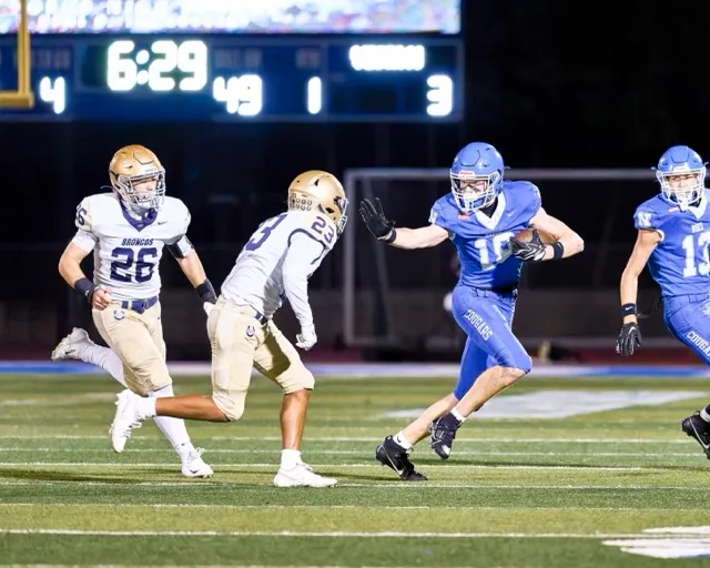 Norco’s Tegan Ogas (18) strikes the Heisman pose as he tries to escape from Vista Murrieta defenders on an out route and fights for a first down